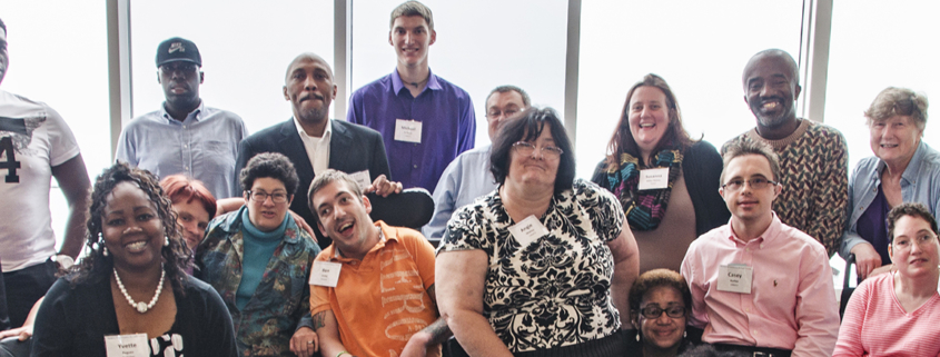 A group of conference attendees poses together, all wearing nametags clipped to their shirts