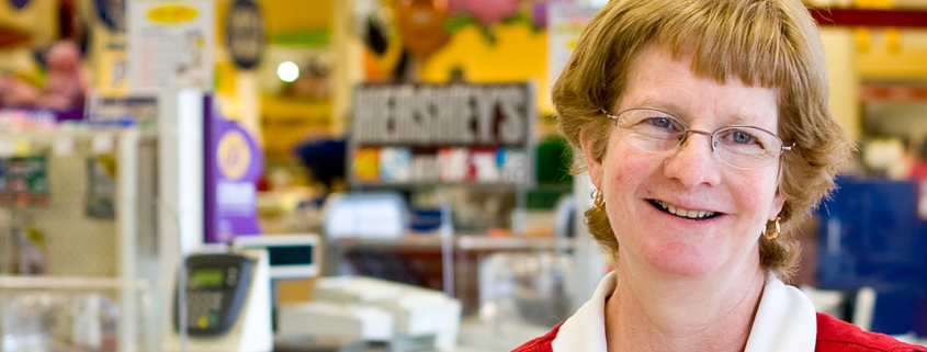 A woman smiles at a cash register in a grocery store