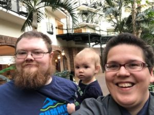 Ivanova Smith takes a selfie and smiles with her husband and child to her right. 