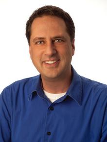 Christiano Sosa, Executive Director of The Arc Colorado, smiles for a photograph wearing a blue polo. 