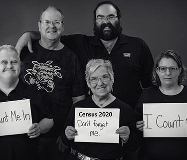 Black and white photo of people holding signs that say "I Count. Count me in. Census 2020"