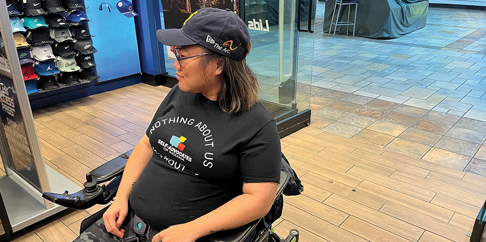 Young woman in a wheelchair shows her new hat custom embroidered with The Arc logo